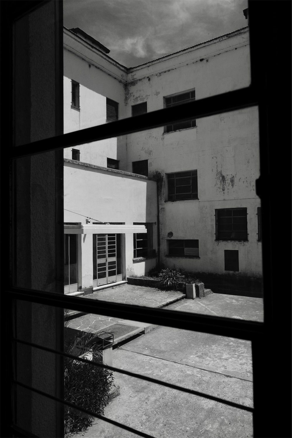 the courtyard of the esma in buenos aires seen through a window pane in black and white