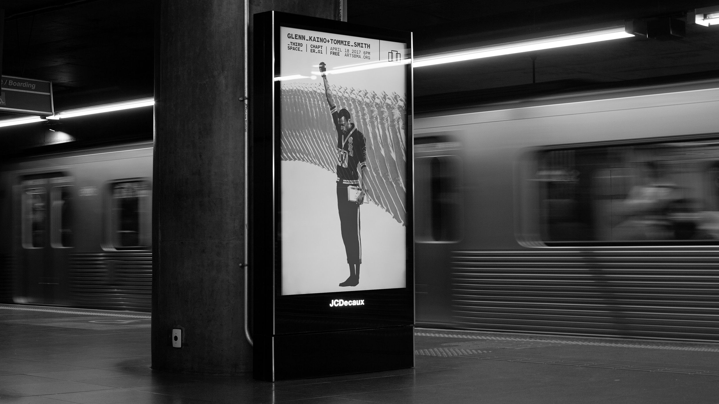 black and white image of poster display in a subway station, train streaking by in motion